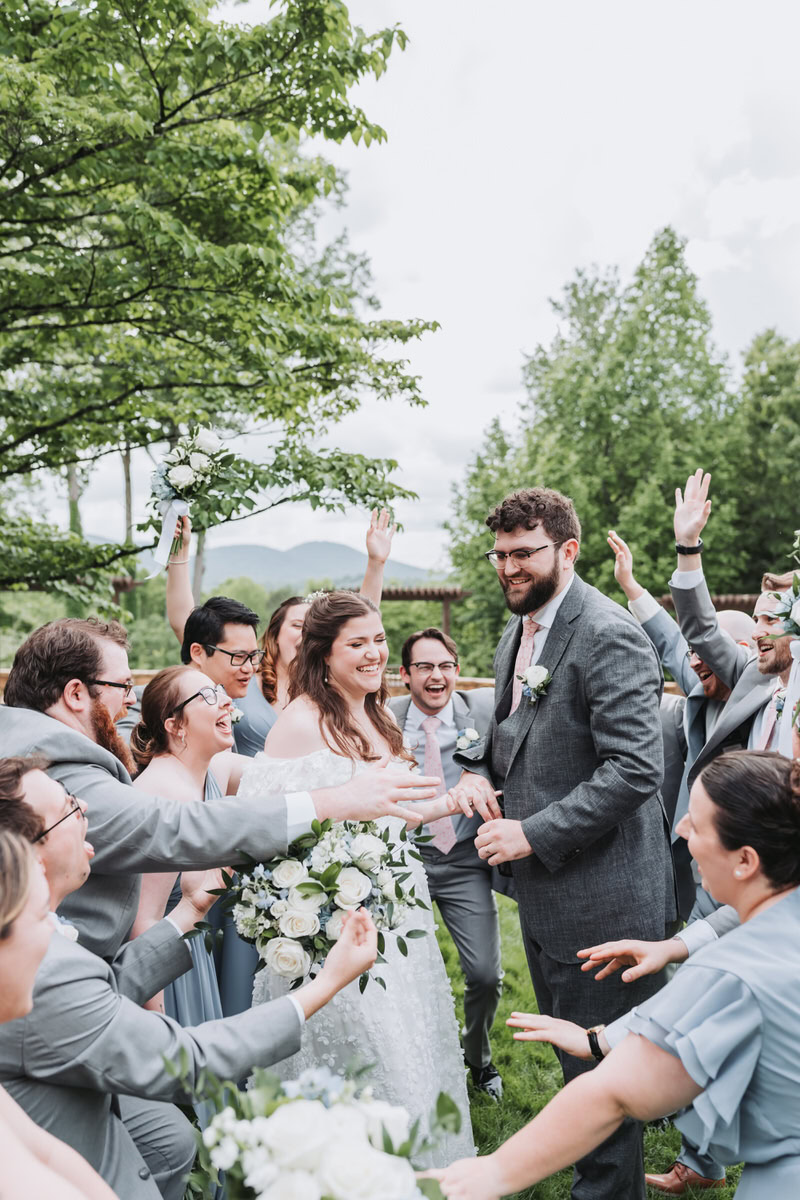 Wedding Party hugs couple as they laugh