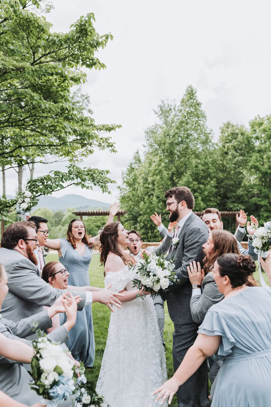 wedding party runs to hug bride and groom as they look at each other