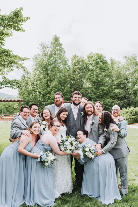 Wedding party gives a big hug to the bride and groom