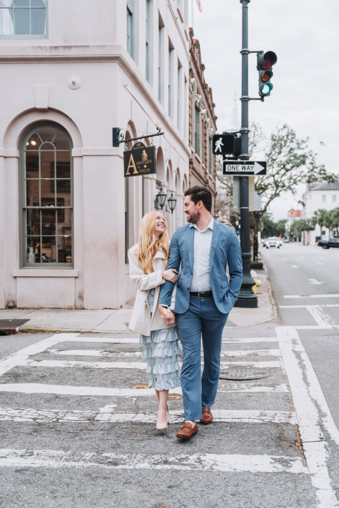 girl holds guys arm as they walk the streets of downtown Charleston.