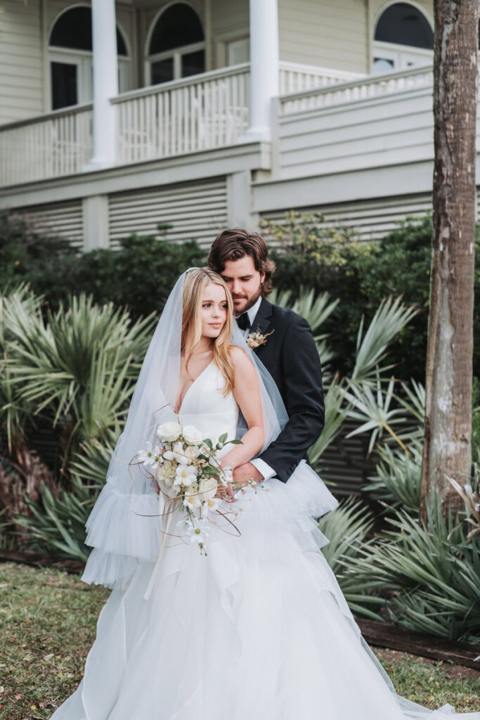 groom holds bride's waist during wedding photos