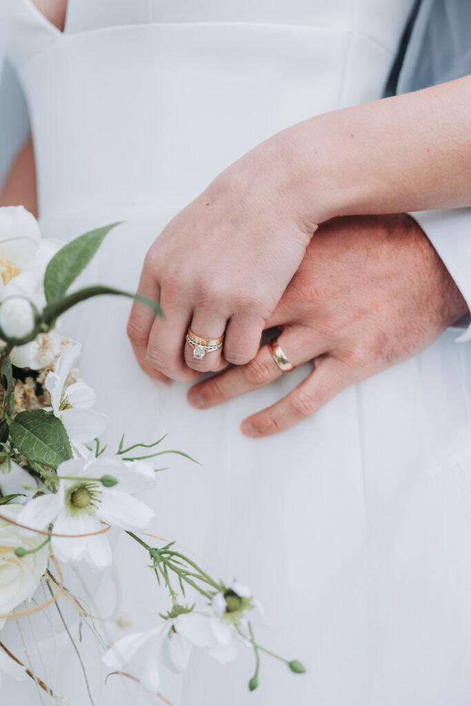 up close photo of bride holding grooms hand and showing their wedding rings