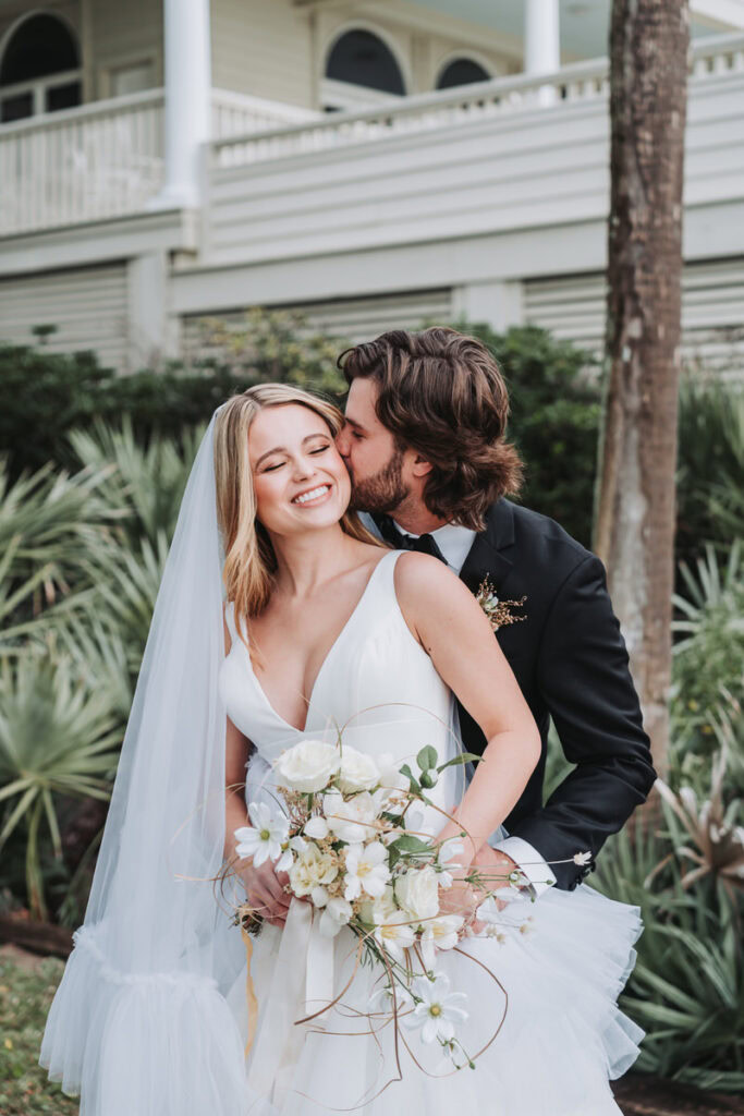 groom kisses bride's cheek as she laughs