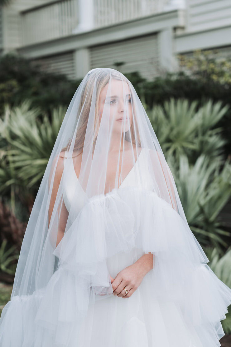 bride is under her veil and looks off during her portrait