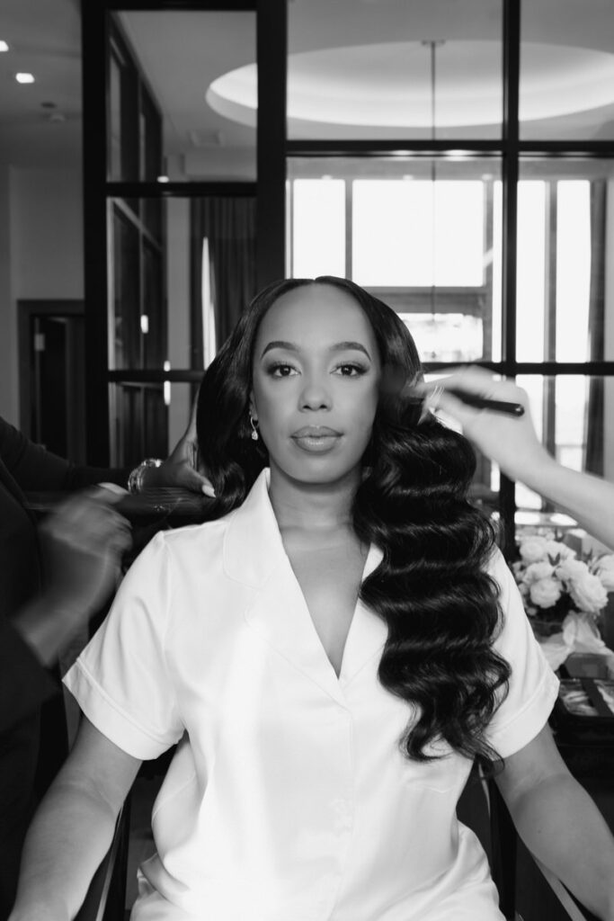 makeup artist touches up bride's hair and makeup