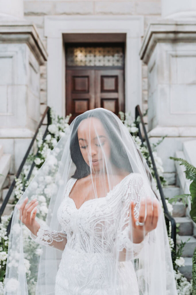 Bride looking down at veil in front of the historic dekalb county courthouse