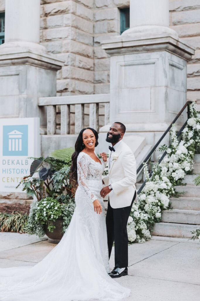 bride and groom laugh while taking wedding portraits at the dekalb history center