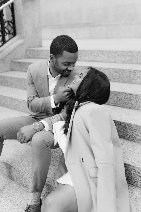 guy holds girl's chin and pulls her in for a kiss on stairs